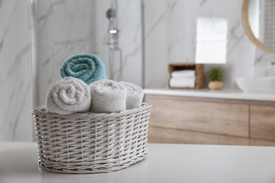 Wicker basket with clean soft towels in bathroom. Space for text