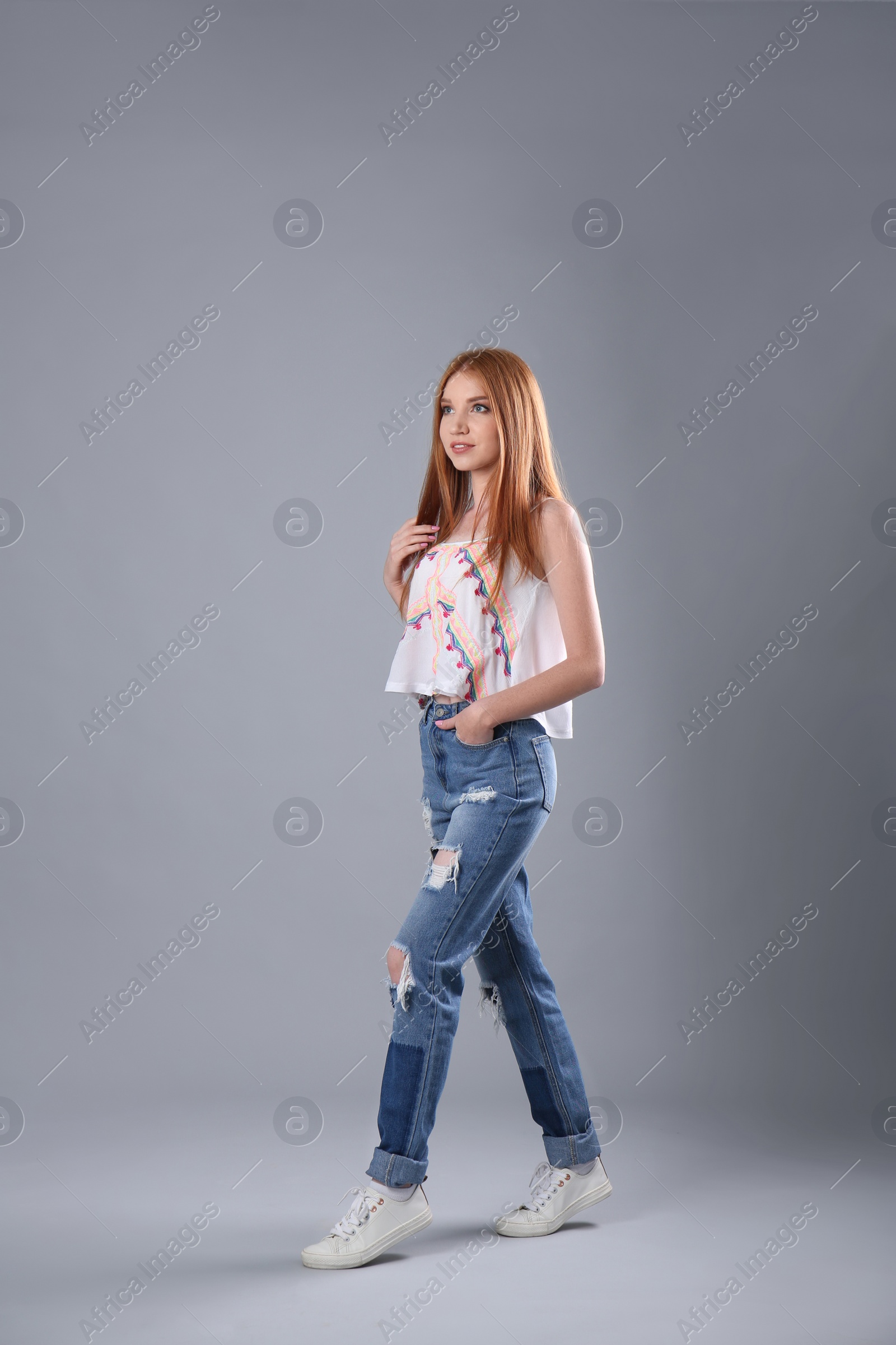 Photo of Young woman in stylish jeans on grey background