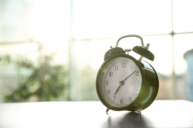 Black alarm clock on table in morning. Space for text