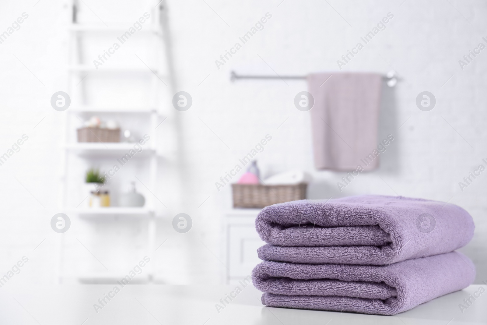 Photo of Stack of fresh towels on table in bathroom. Space for text