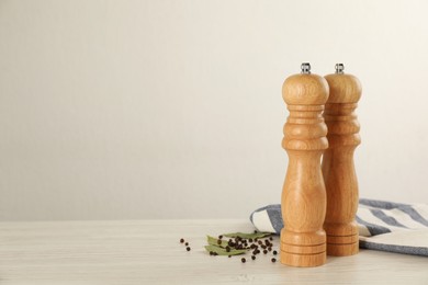 Photo of Wooden salt and pepper shakers with napkin on table against white background, space for text. Spice mill