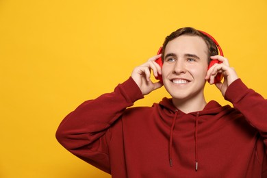 Photo of Handsome young man with headphones on yellow background. Space for text