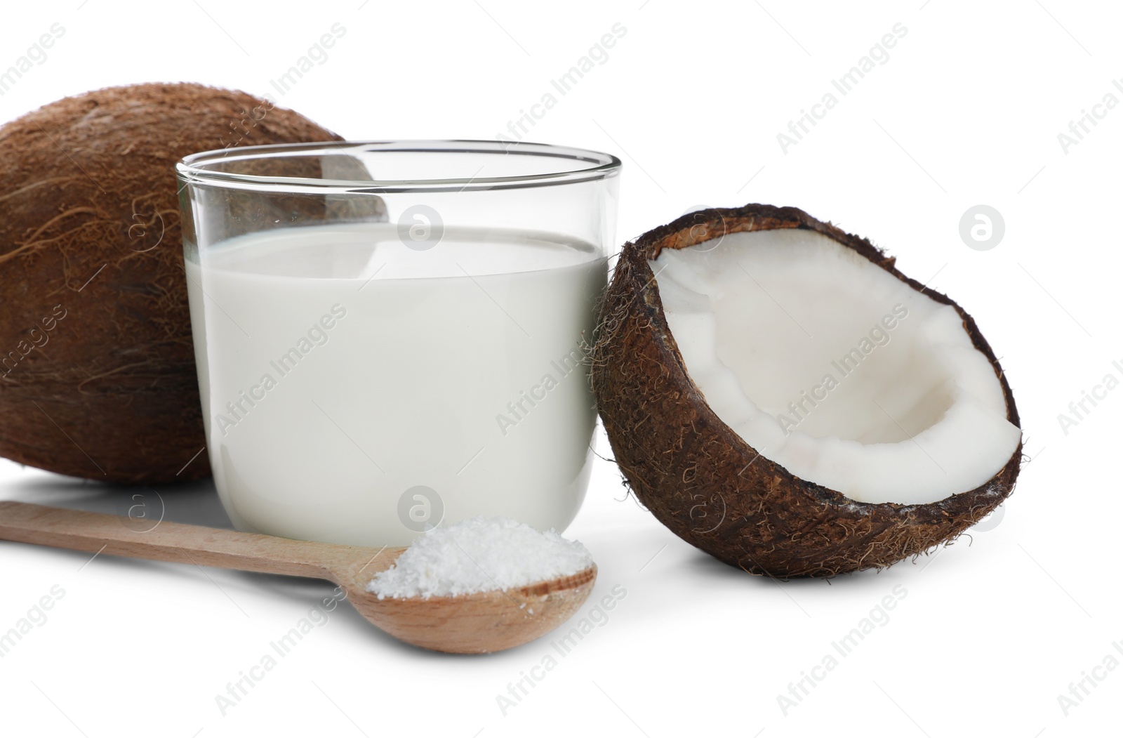 Photo of Glass of delicious coconut milk, spoon with flakes and nuts isolated on white