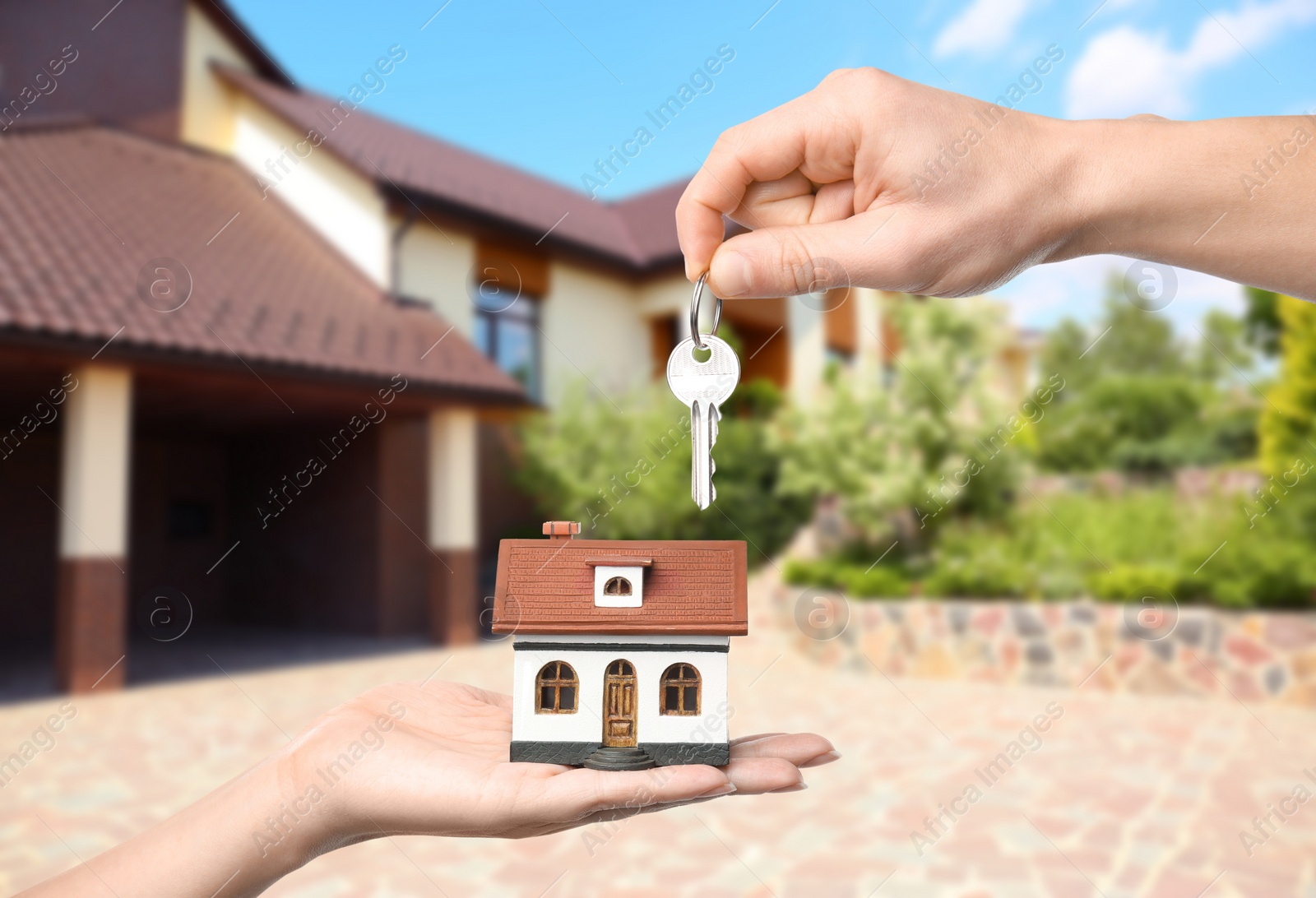 Image of Real estate agent giving key to woman with house model against villa, closeup