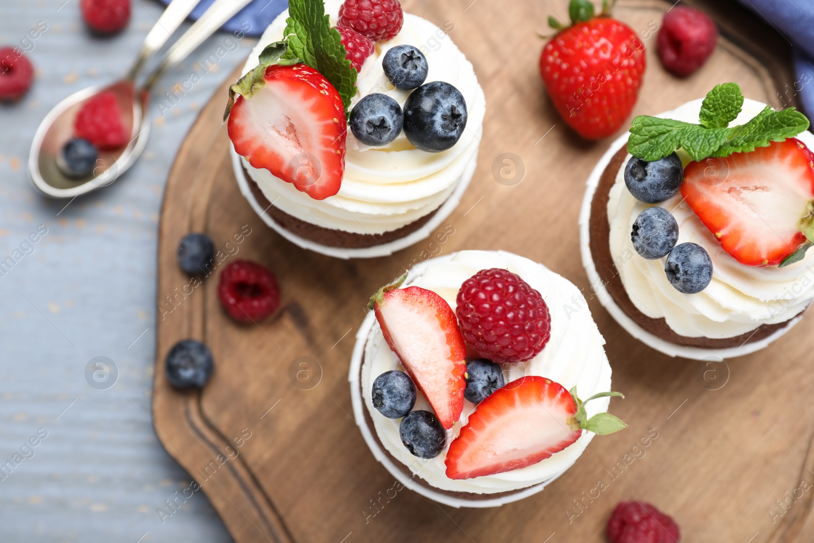 Photo of Sweet cupcakes with fresh berries on wooden table, flat lay