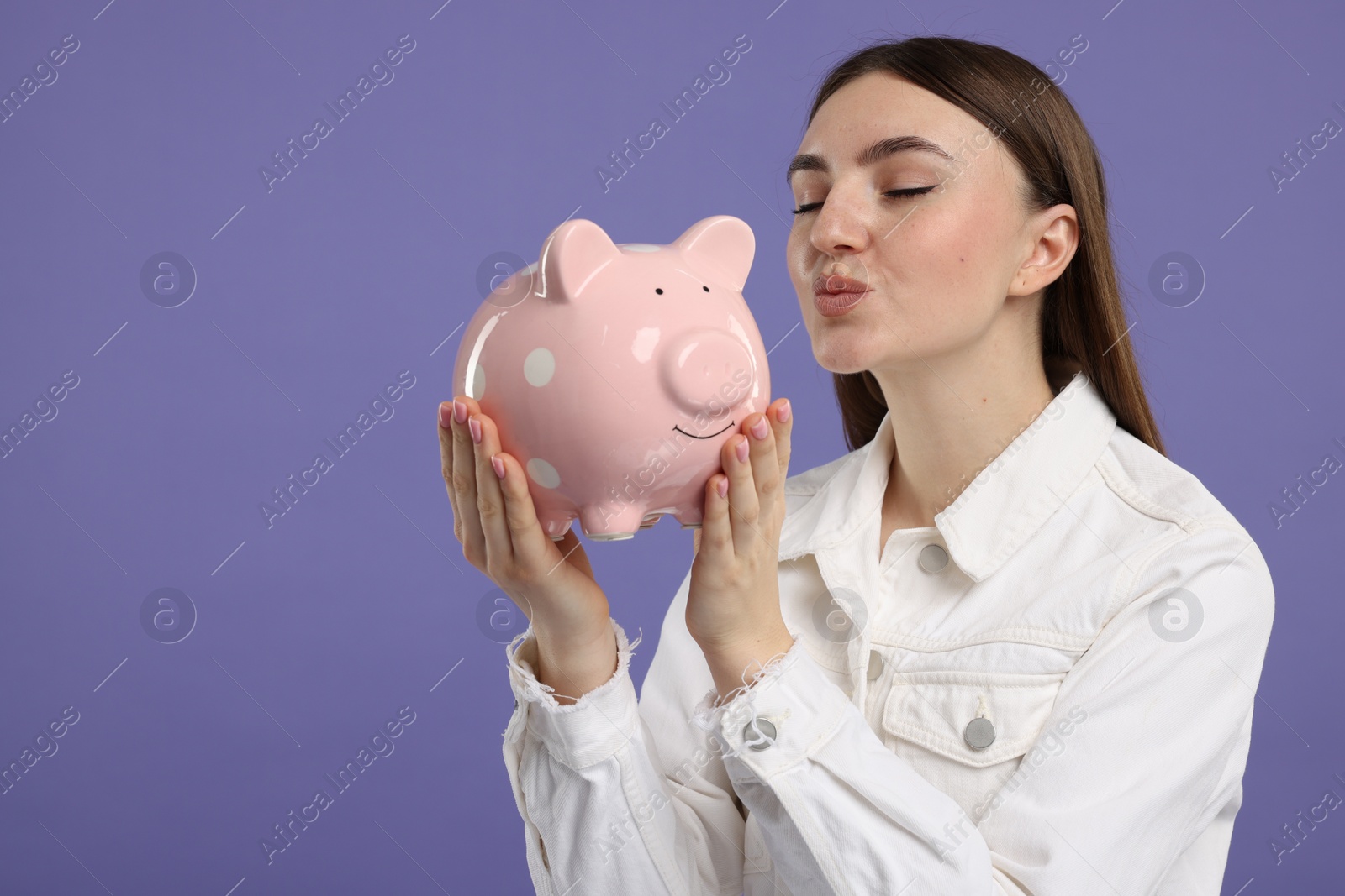 Photo of Woman with piggy bank on purple background, space for text