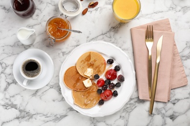 Photo of Delicious pancakes with berries and butter served for breakfast on table