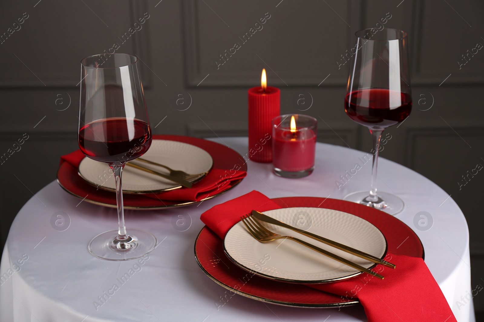 Photo of Place setting with candles on white table. Romantic dinner