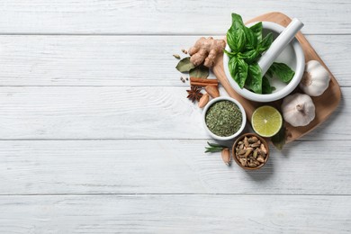 Photo of Flat lay composition with different natural spices and herbs on white wooden table, space for text