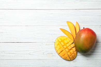 Photo of Flat lay composition with ripe mangoes and space for text on white wooden background