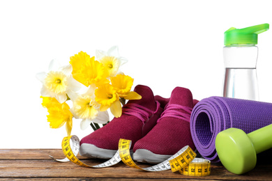 Photo of Composition with spring flowers and sports items on wooden table against white background