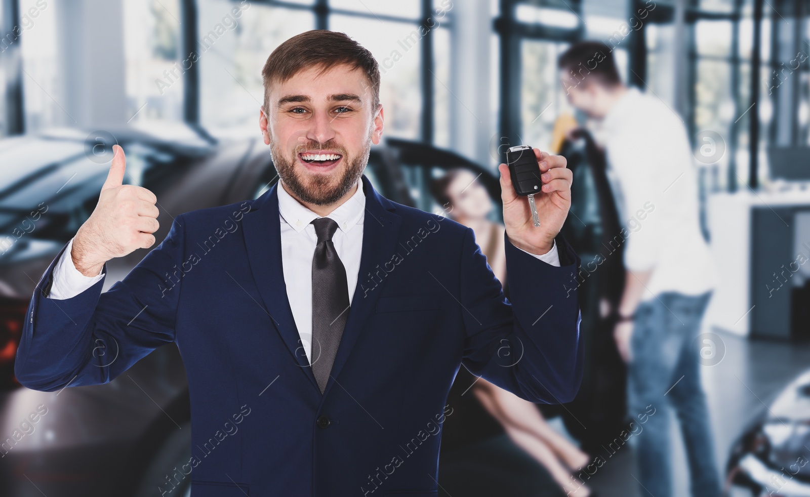 Image of Happy salesman with key in car salon