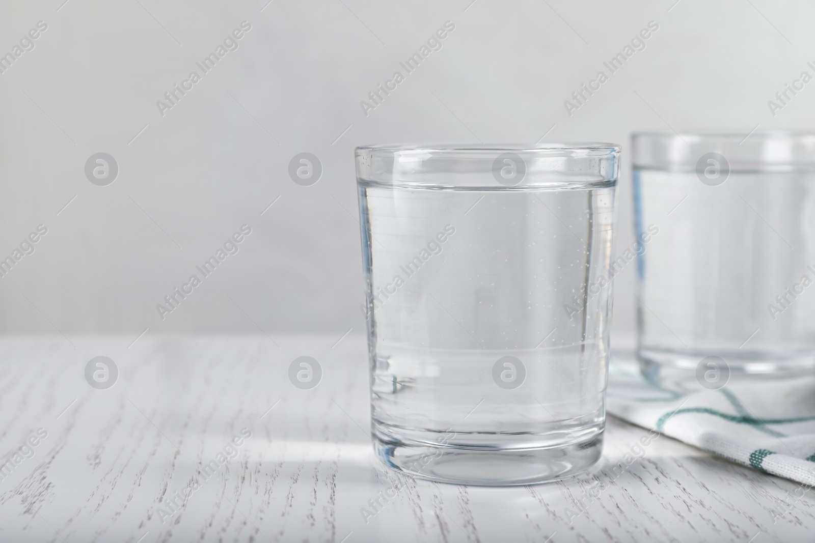 Photo of Glasses of soda water on white wooden table. Space for text