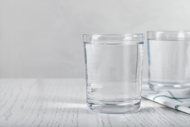 Photo of Glasses of soda water on white wooden table. Space for text