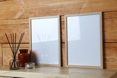 Empty frames with other decor on table near wooden wall. Mockup for design