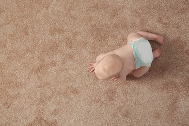 Photo of Cute little baby crawling on carpet indoors, top view with space for text