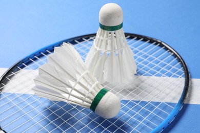 Photo of Feather badminton shuttlecocks and racket on blue background, closeup
