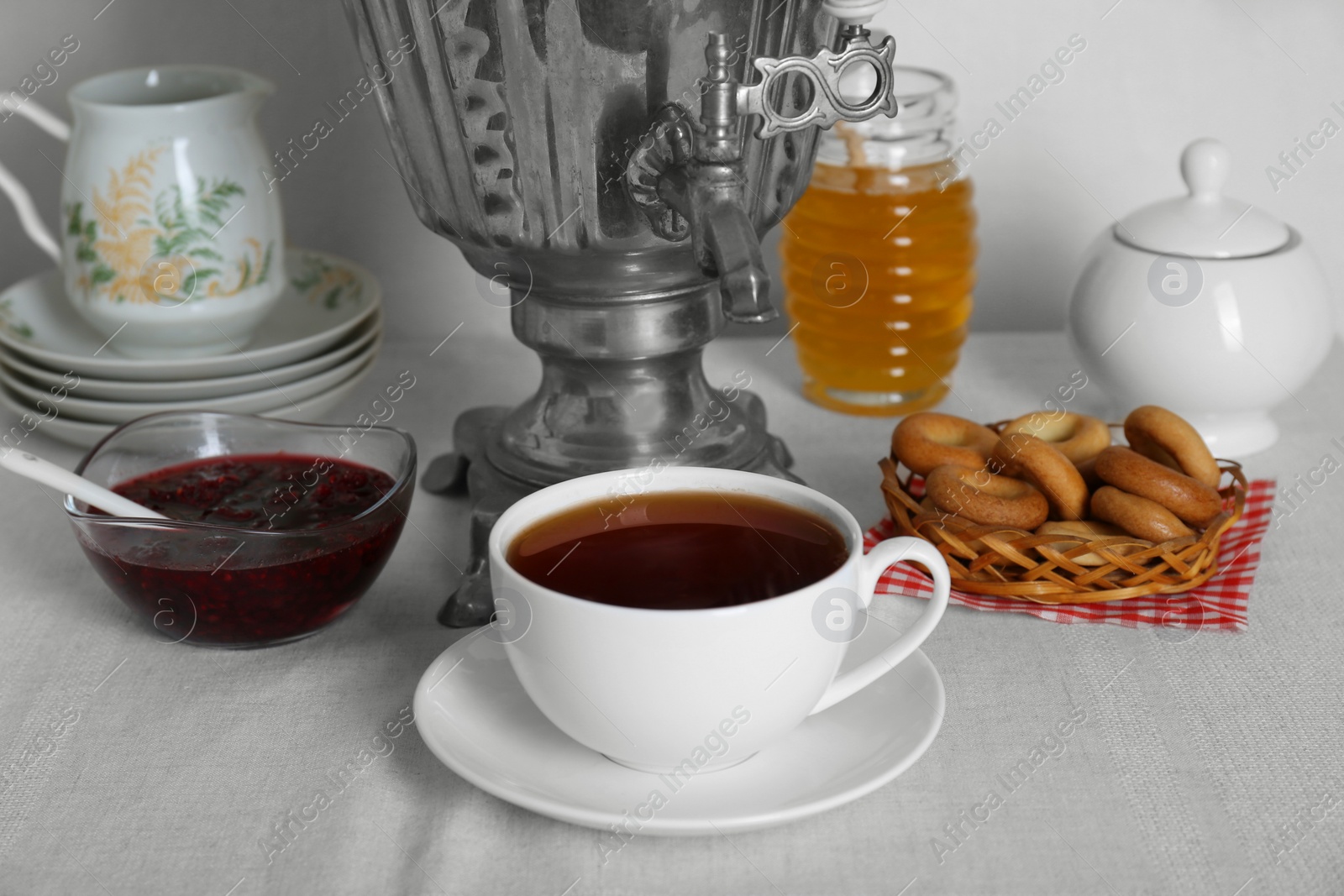 Photo of Composition with delicious ring shaped Sushki (dry bagels) and tea on white tablecloth near wall