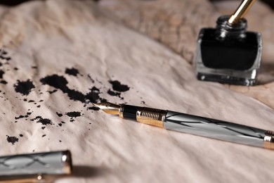 Photo of Fountain pen and inkwell on vintage parchment with ink stains, closeup