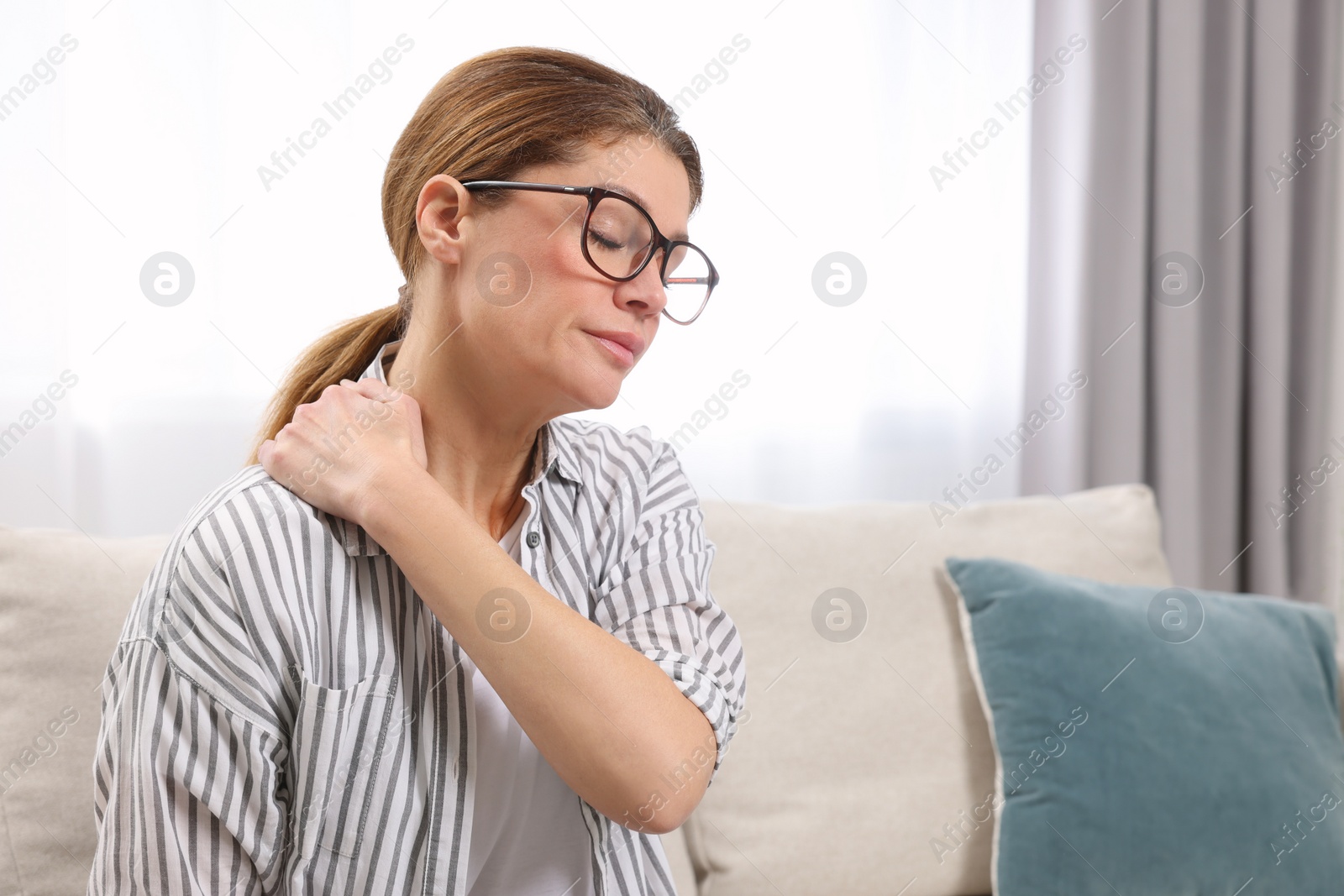 Photo of Woman suffering from pain in shoulder indoors. Arthritis symptoms