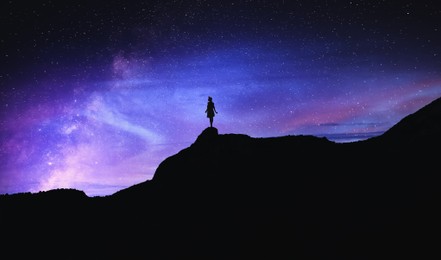 Image of Silhouette of woman in mountains under beautiful starry sky at night
