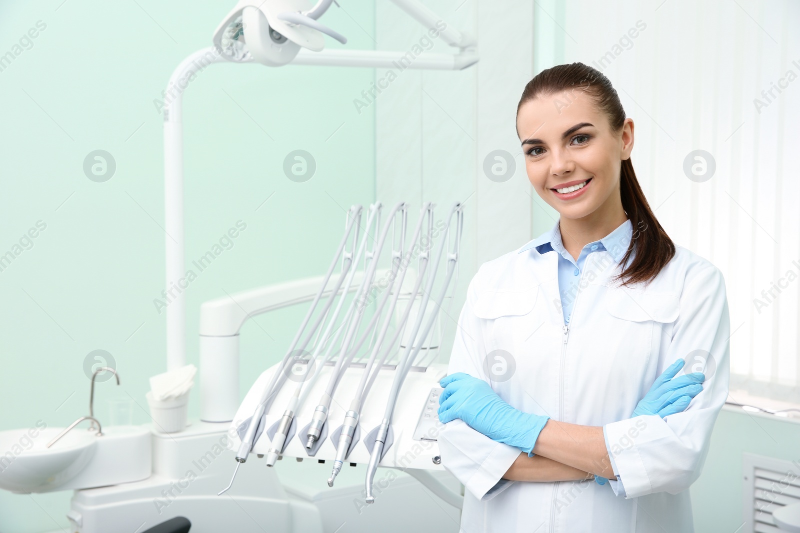 Photo of Young female dentist in white coat at workplace. Space for text