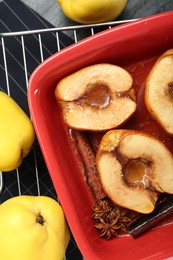 Photo of Tasty baked quinces with anise and honey in dish on black table, flat lay