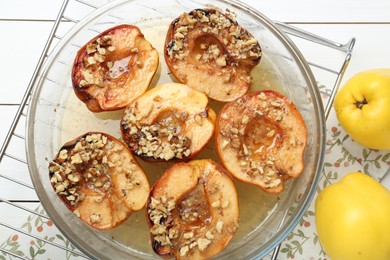 Photo of Delicious baked quinces with nuts in bowl and fresh fruits on white wooden table, flat lay