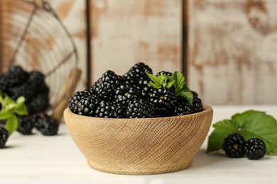 Photo of Bowl with fresh ripe blackberries on white wooden table, closeup