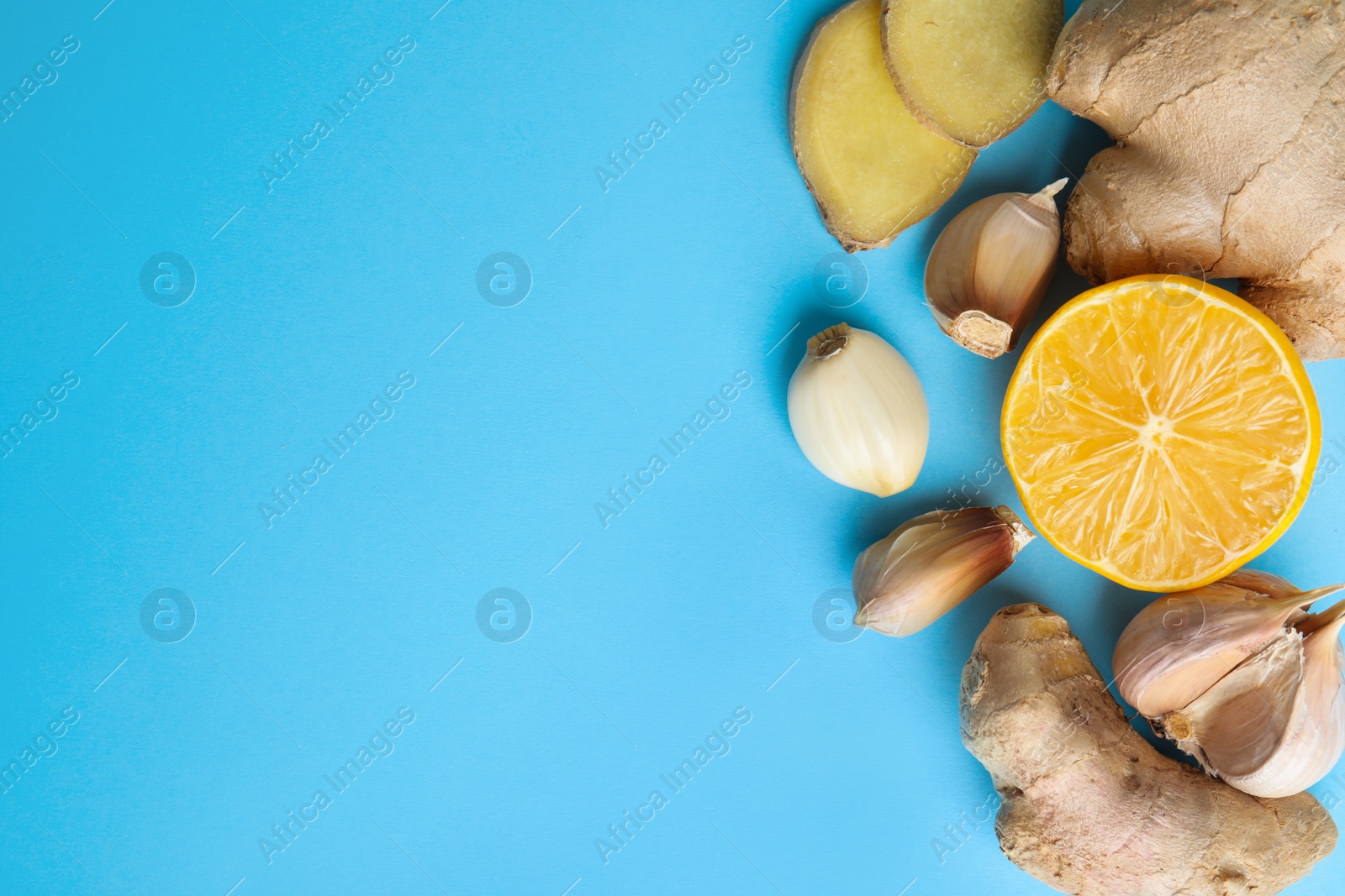 Photo of Fresh garlic and other natural cold remedies on light blue background, flat lay. Space for text