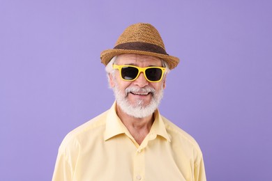 Photo of Portrait of stylish grandpa with sunglasses and hat on purple background