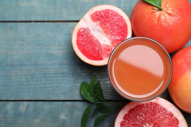 Photo of Tasty freshly made grapefruit juice and fruits on blue wooden table, flat lay. Space for text