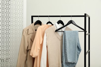 Photo of Rack with different stylish women's clothes near light wall indoors