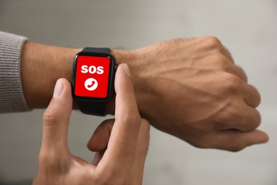 Man using SOS function on smartwatch indoors, closeup