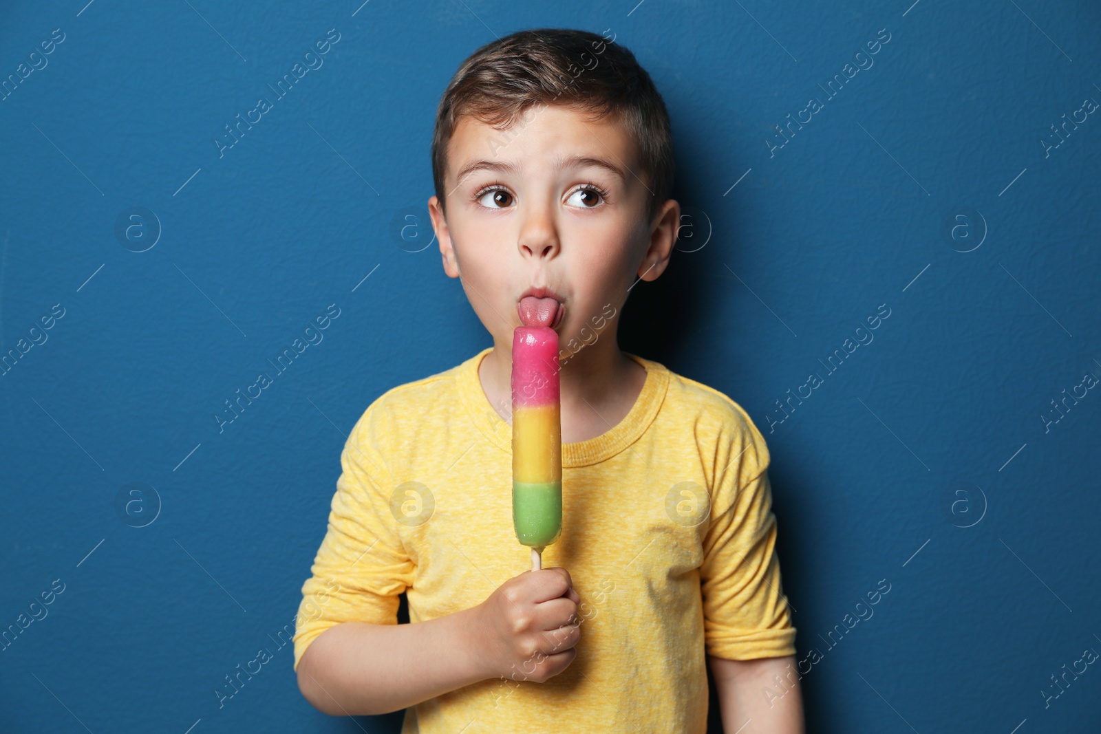 Photo of Adorable little boy with delicious ice cream against color background