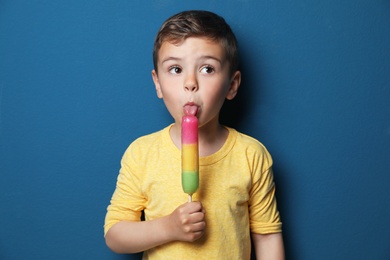 Adorable little boy with delicious ice cream against color background