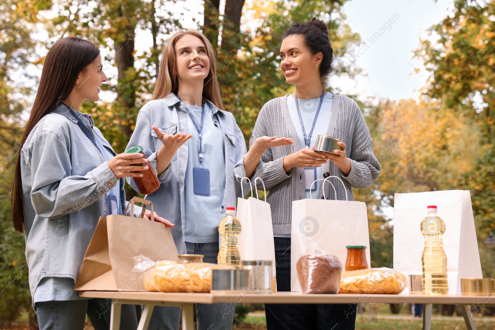 Photo of Group of volunteers packing food products at table in park