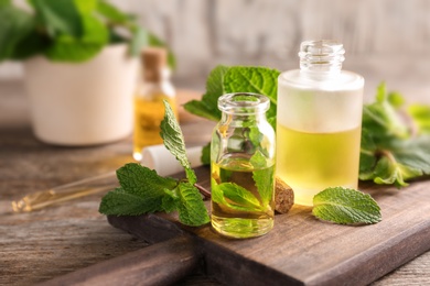 Photo of Bottles of essential oil and mint leaves on table