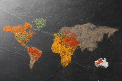 Photo of World map of different spices on dark textured table, flat lay