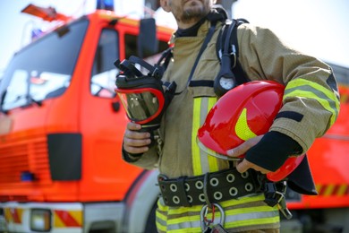 Photo of Firefighter in uniform with helmet and mask outdoors, selective focus
