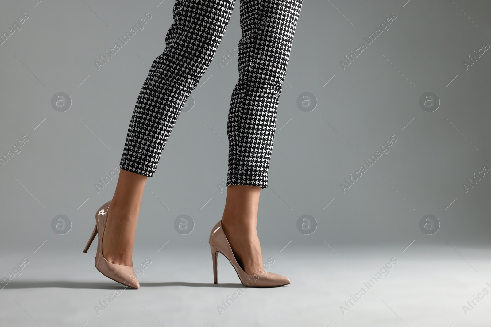 Photo of Businesswoman in beige shoes on grey background, closeup