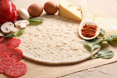 Photo of Pizza base and products on light textured table, closeup