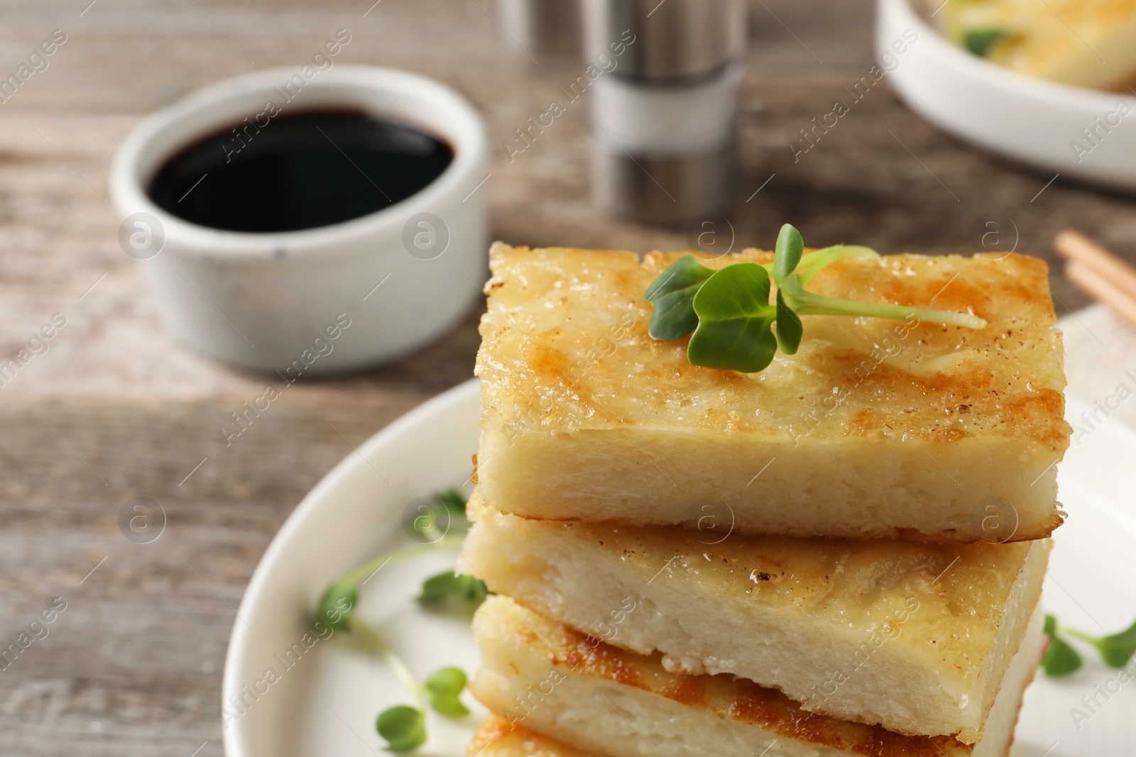 Photo of Delicious turnip cake with microgreens served on wooden table, closeup