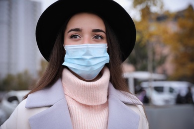 Young woman in medical face mask walking outdoors. Personal protection during COVID-19 pandemic