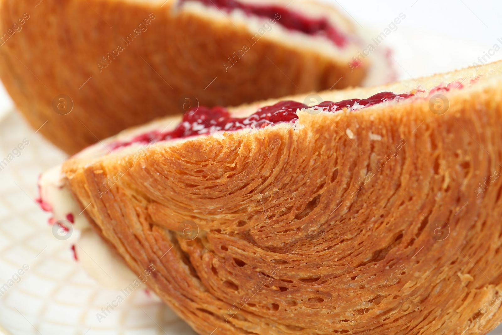 Photo of Round croissant with jam on plate, closeup. Tasty puff pastry