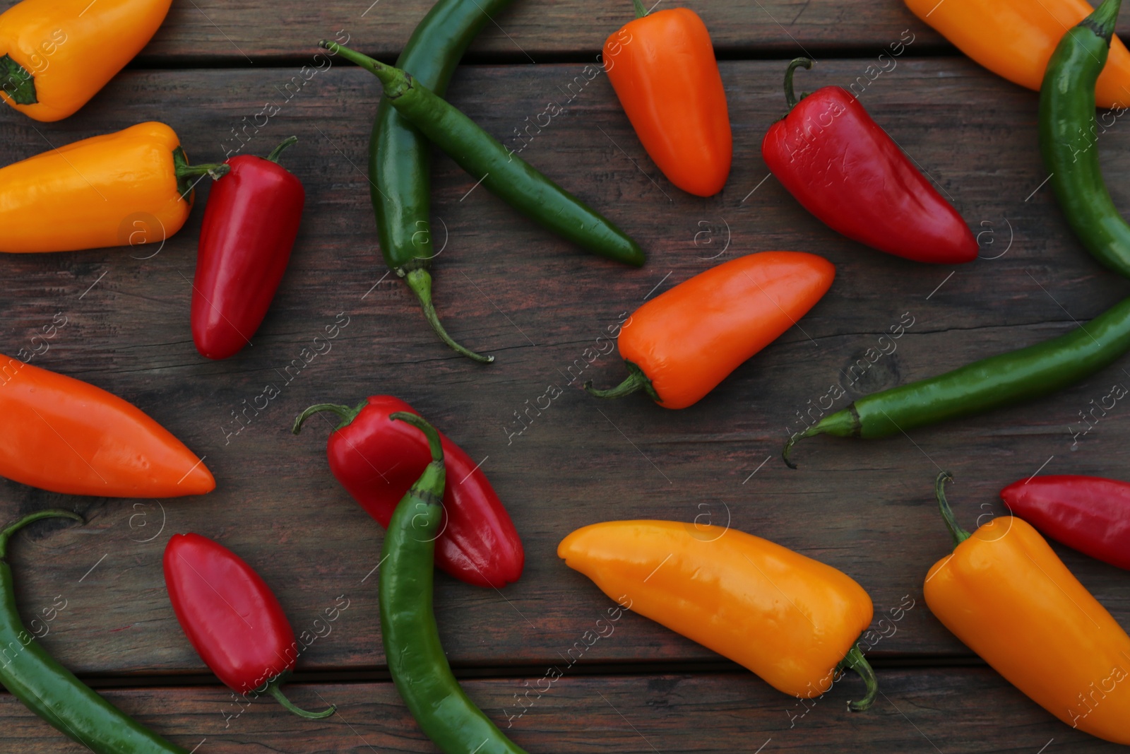 Photo of Different ripe bell peppers on wooden table, flat lay