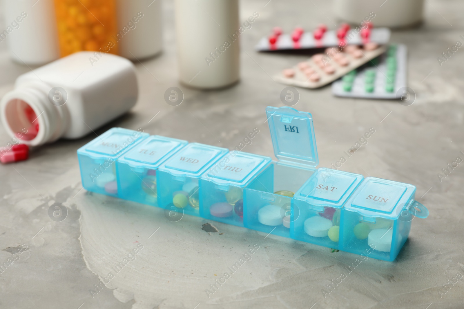Photo of Plastic box with different pills on light grey stone table