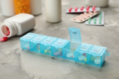 Plastic box with different pills on light grey stone table
