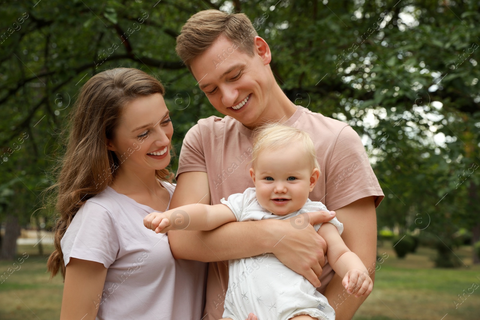 Photo of Parents with their cute baby spending time together outdoors. Happy family