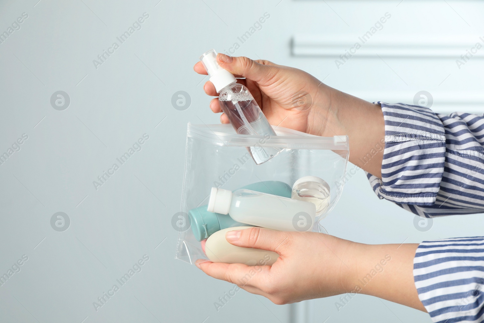 Photo of Woman packing cosmetic travel kit indoors, closeup. Space for text